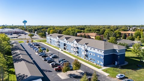 A large blue building with a parking lot in front of it.