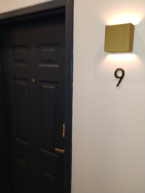A black door with a gold number 9 on the wall.