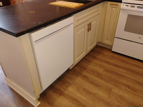 A kitchen with white cabinets and a black countertop.