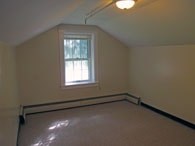 A room with a window and a white wall.