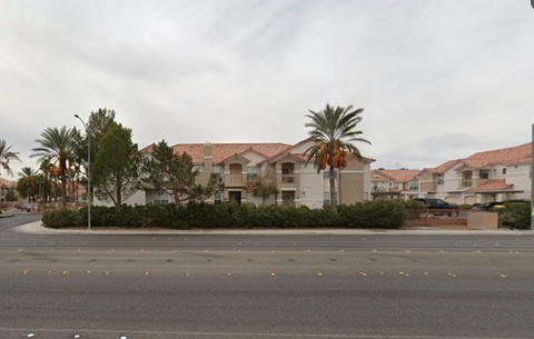 A street view of a residential area with houses and palm trees.