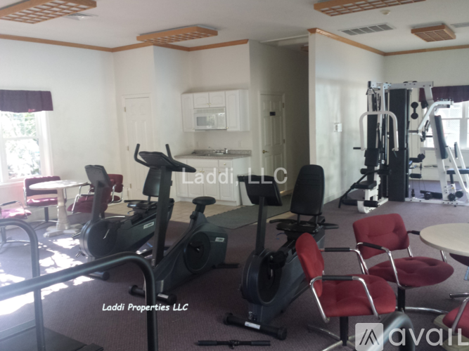 A gym with exercise equipment and a sign that says "Laddi Properties LLC".