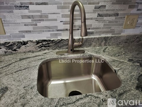 A modern kitchen sink with a chrome faucet and a marble countertop.