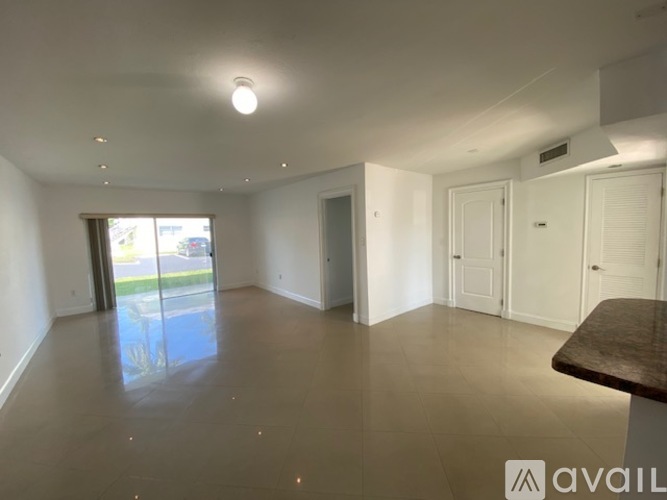 A spacious room with a table and a sliding glass door leading outside.