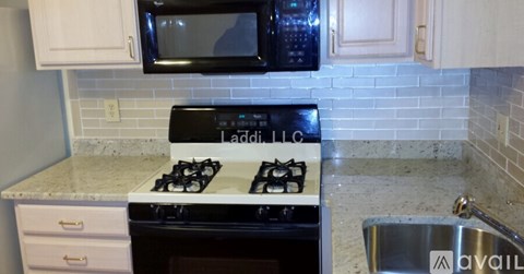A kitchen with a white stove top and a black microwave above it.