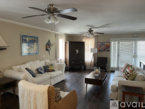 A living room with a white couch and a ceiling fan.