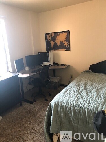 A bedroom with a bed, desk, and computer setup.