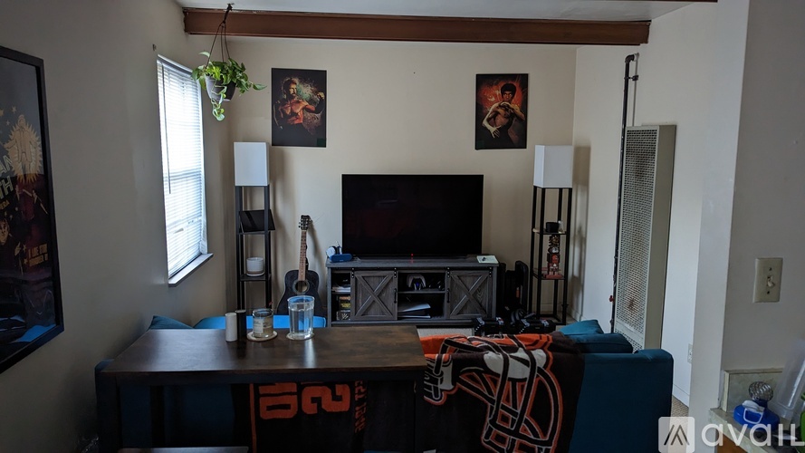 A living room with a TV, a plant, and a picture on the wall.