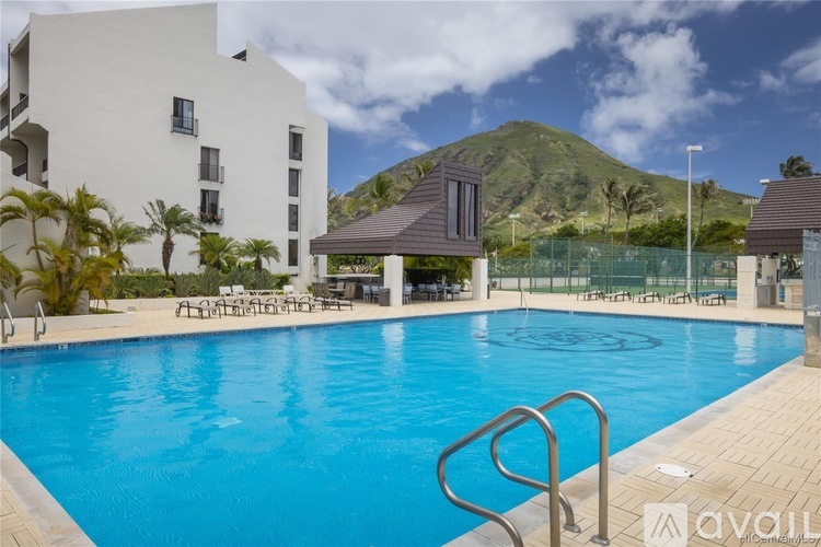 A large swimming pool in front of a white building with a mountain in the background.