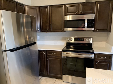 A kitchen with brown cabinets and a stainless steel refrigerator.