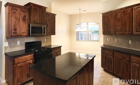 A kitchen with wooden cabinets and black countertops.