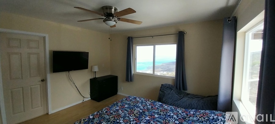 A bedroom with a bed, a ceiling fan, and a flat screen TV.