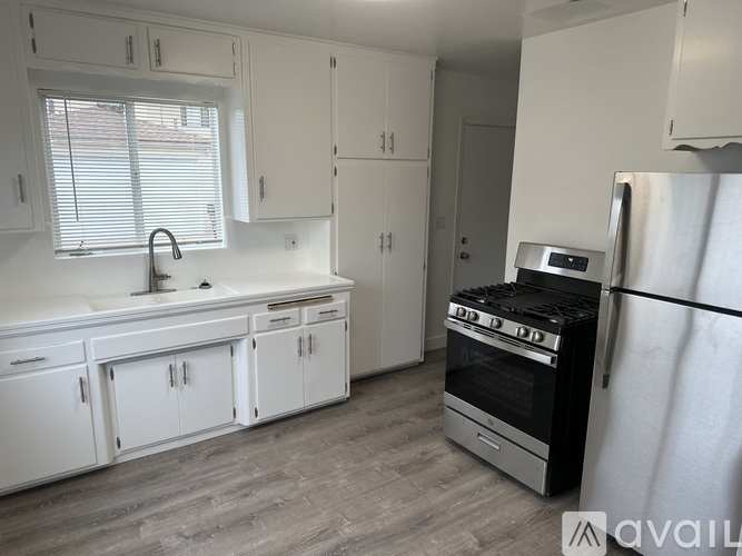 A kitchen with white cabinets and a stainless steel refrigerator.