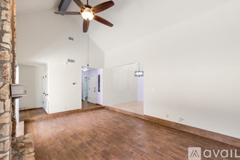 A room with a ceiling fan and wooden flooring.