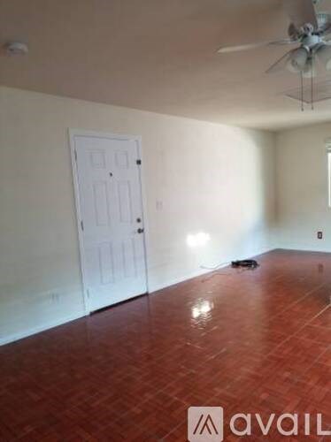 A room with a white door and a ceiling fan.
