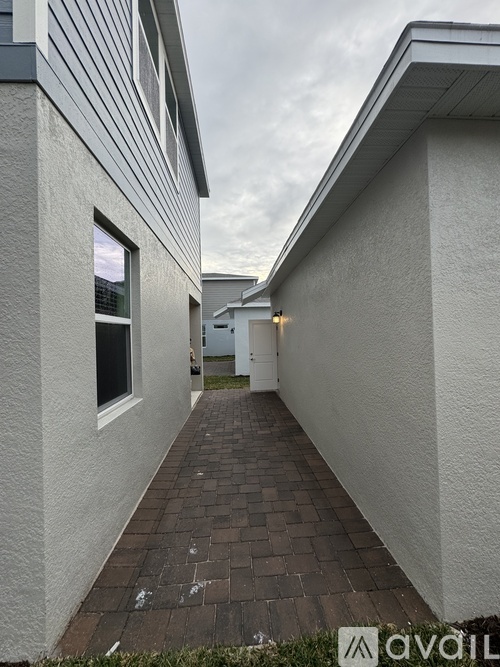 A long, narrow walkway between two buildings with a cloudy sky in the background.
