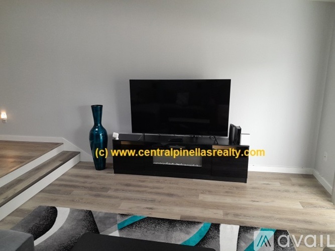 A living room with a black couch and a blue vase on a wooden table.