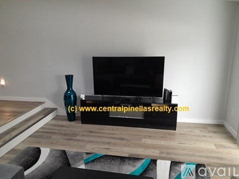 A living room with a black couch and a blue vase on a wooden table.