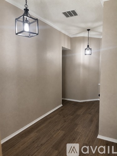A hallway with wooden floors and two hanging lights.