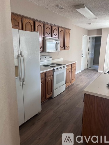A kitchen with white appliances and wooden cabinets.