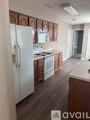 A kitchen with white appliances and wooden cabinets.