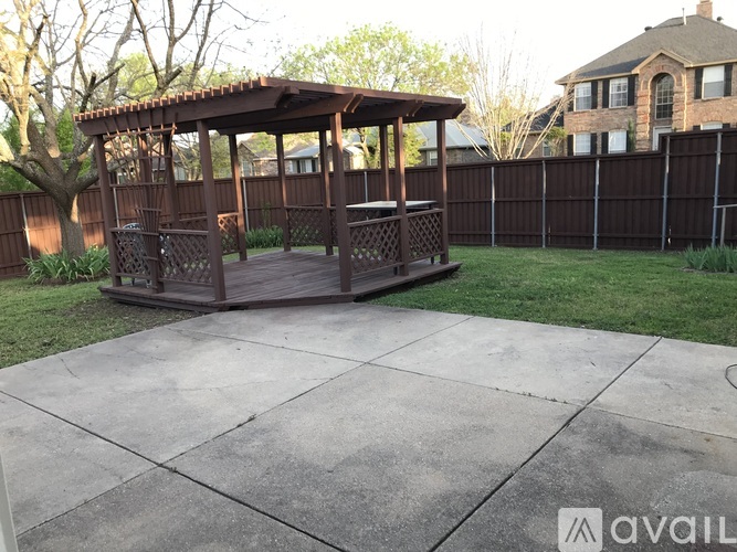 A gazebo is situated in a backyard with a concrete patio.