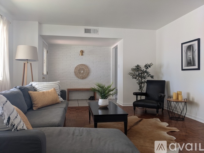 A living room with a grey couch, a black chair, and a wooden coffee table.
