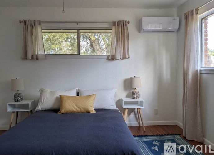 A bedroom with a bed, two lamps, and a window with curtains.