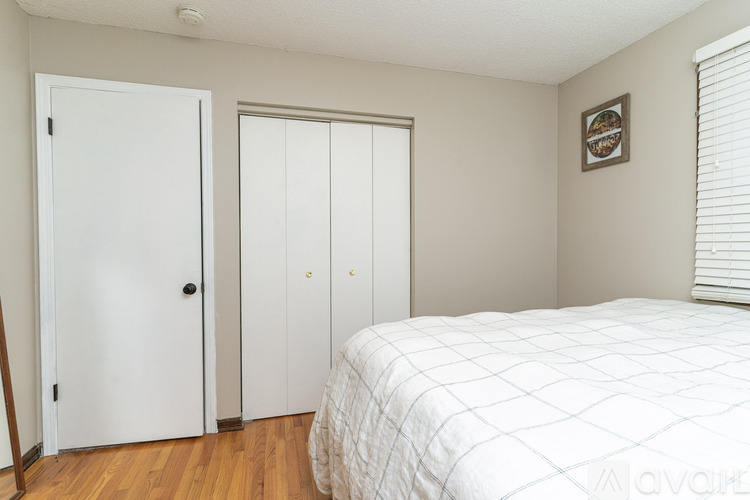 A bedroom with a bed, two doors, and a picture on the wall.