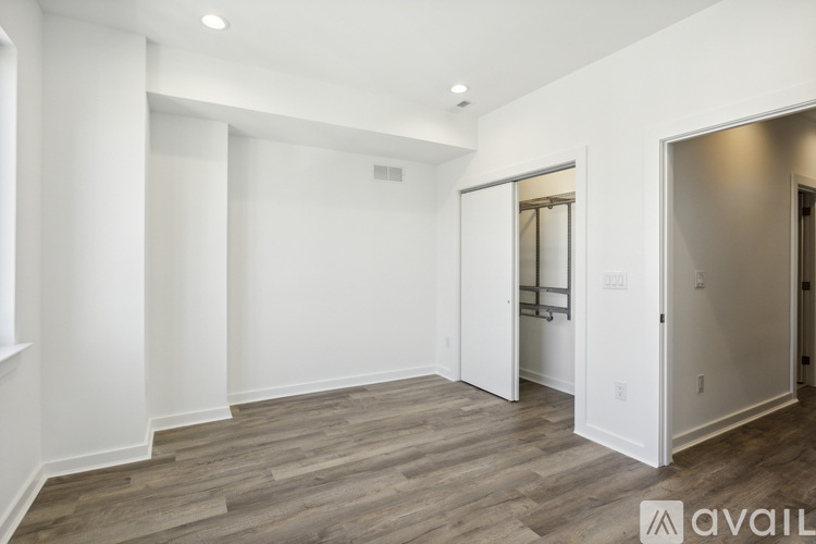 A spacious room with wood flooring and white walls.