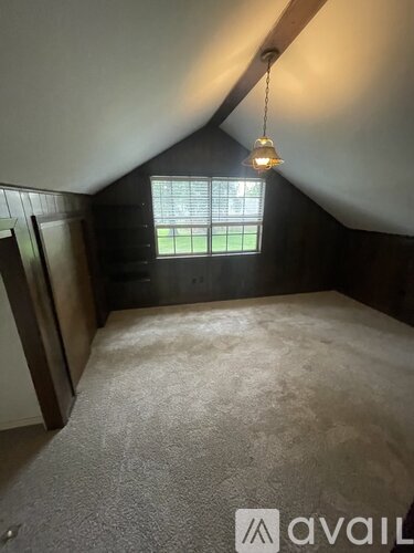 A bedroom with a bed, window, and a hanging light fixture.
