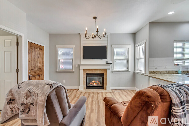 A living room with a fireplace and two chairs covered with blankets.