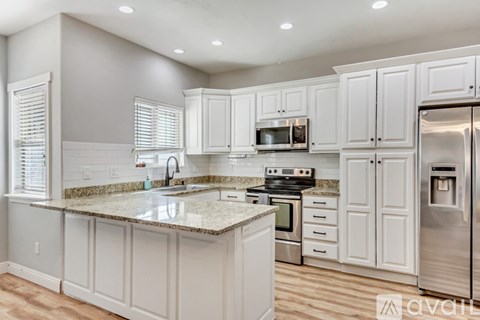 A kitchen with white cabinets and a granite countertop.
