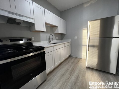 A modern kitchen with white cabinets and stainless steel appliances.