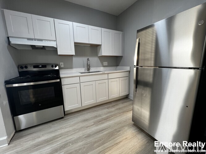 A kitchen with white cabinets and a stainless steel refrigerator.