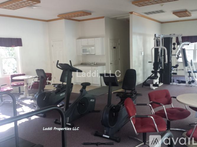 A gym with exercise equipment and a sign that says "Laddi Properties LLC".
