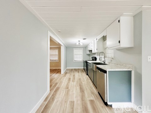 A kitchen with white cabinets and a wooden floor.