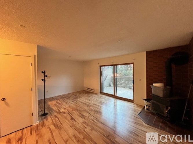 A room with wooden flooring and a fireplace with a white mantlepiece.