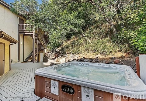 A hot tub is surrounded by a deck and a staircase leading to a house.