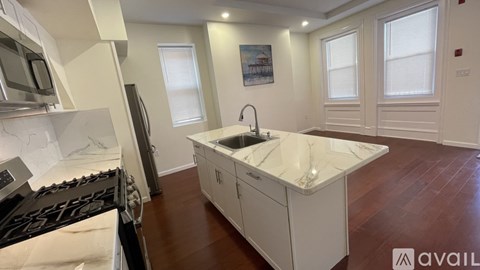 A kitchen with white cabinets and a marble countertop.