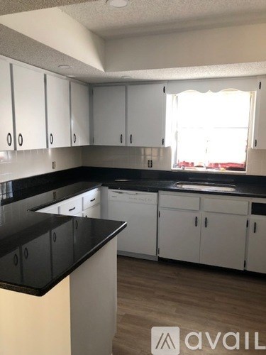 A kitchen with white cabinets and black countertops.