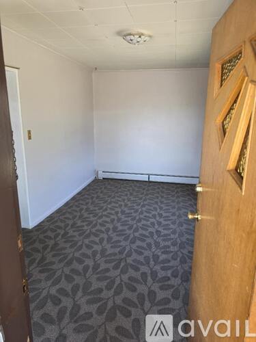 A room with a carpeted floor and a wooden door.