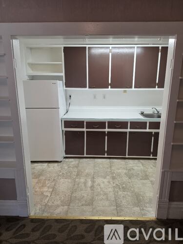 A white refrigerator and freezer are in a kitchen with brown cabinets.