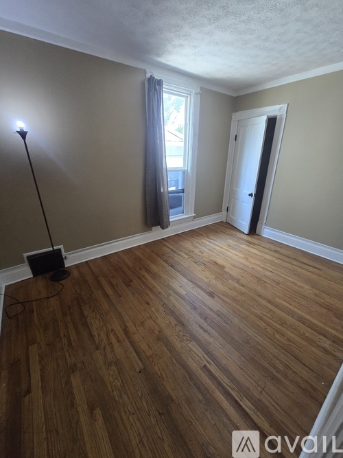 A room with wooden flooring and a window with curtains.
