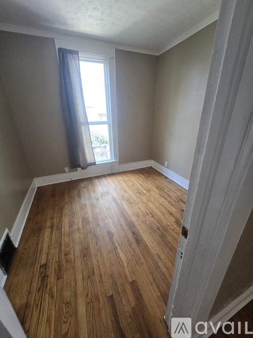A room with wooden flooring and a window with blue curtains.