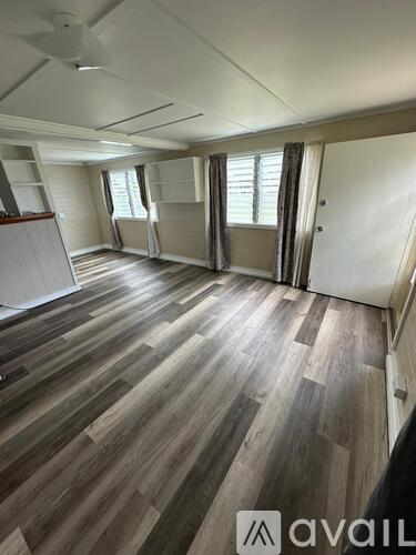 A room with wooden flooring and a window with curtains.