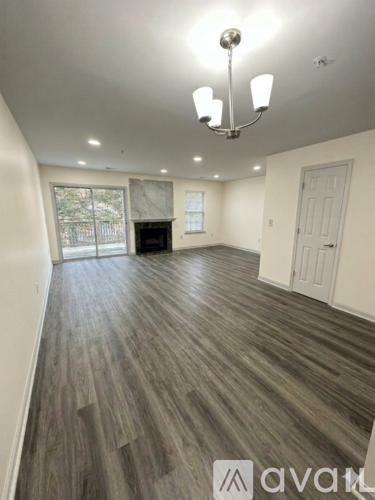 A spacious room with wooden flooring and a chandelier.