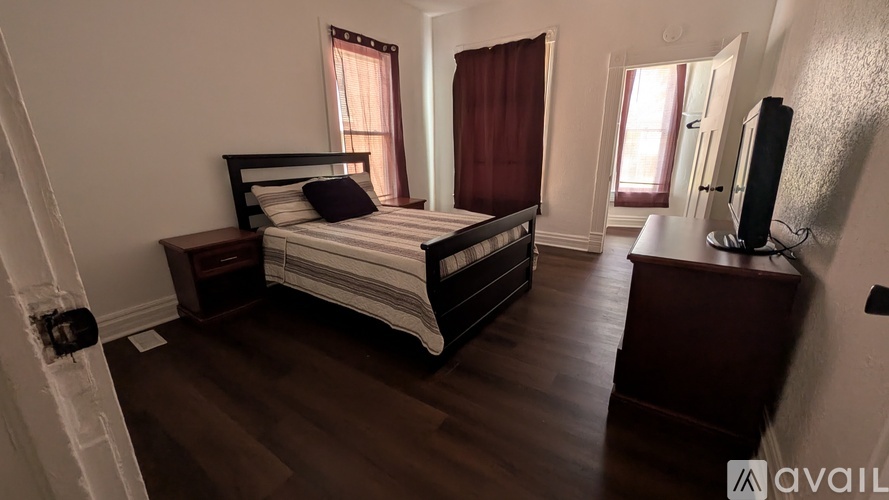A bedroom with a large bed and a wooden dresser.