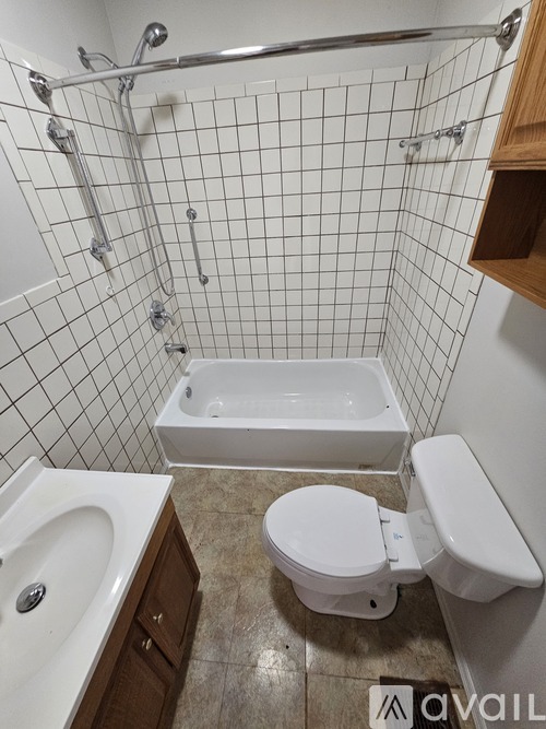 A white toilet sits next to a white bathtub in a bathroom with white tiled walls.