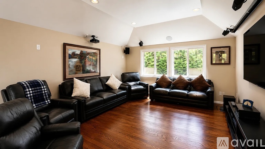 A living room with black leather furniture and a painting on the wall.